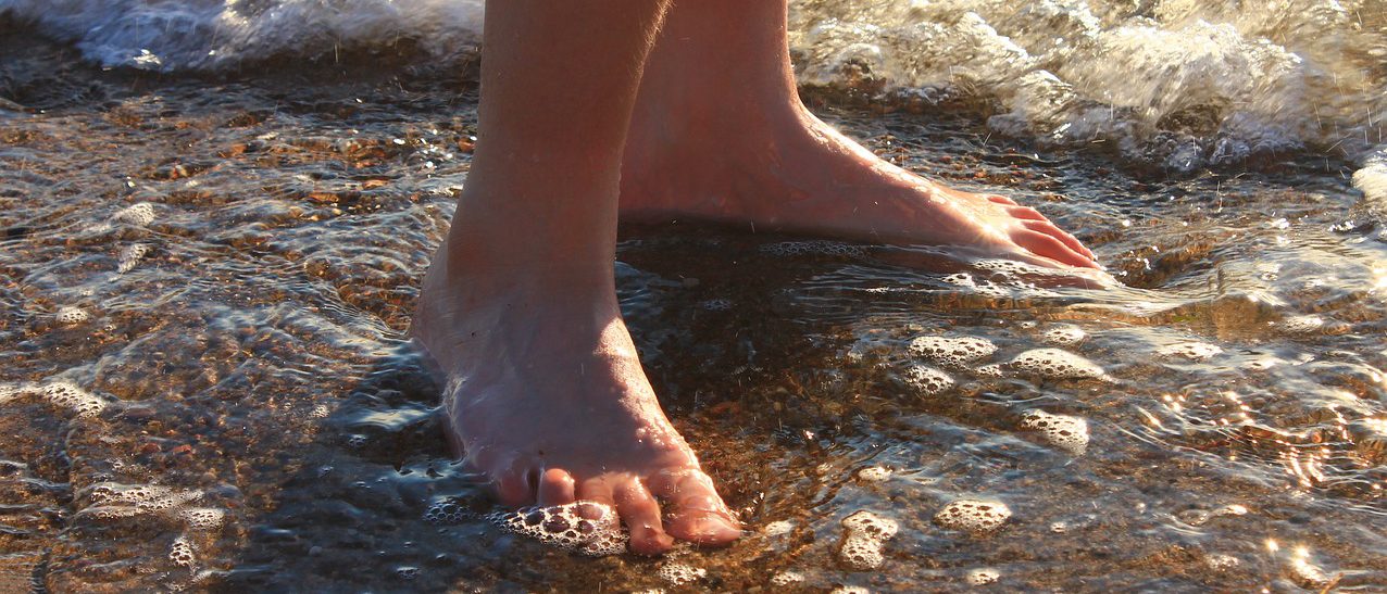 Bild på fötter i vattenbryn.
