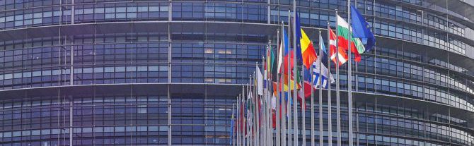 Bild på Europaparlamentet med flaggor på rad utanför som representerar alla EU:s medlemsstater